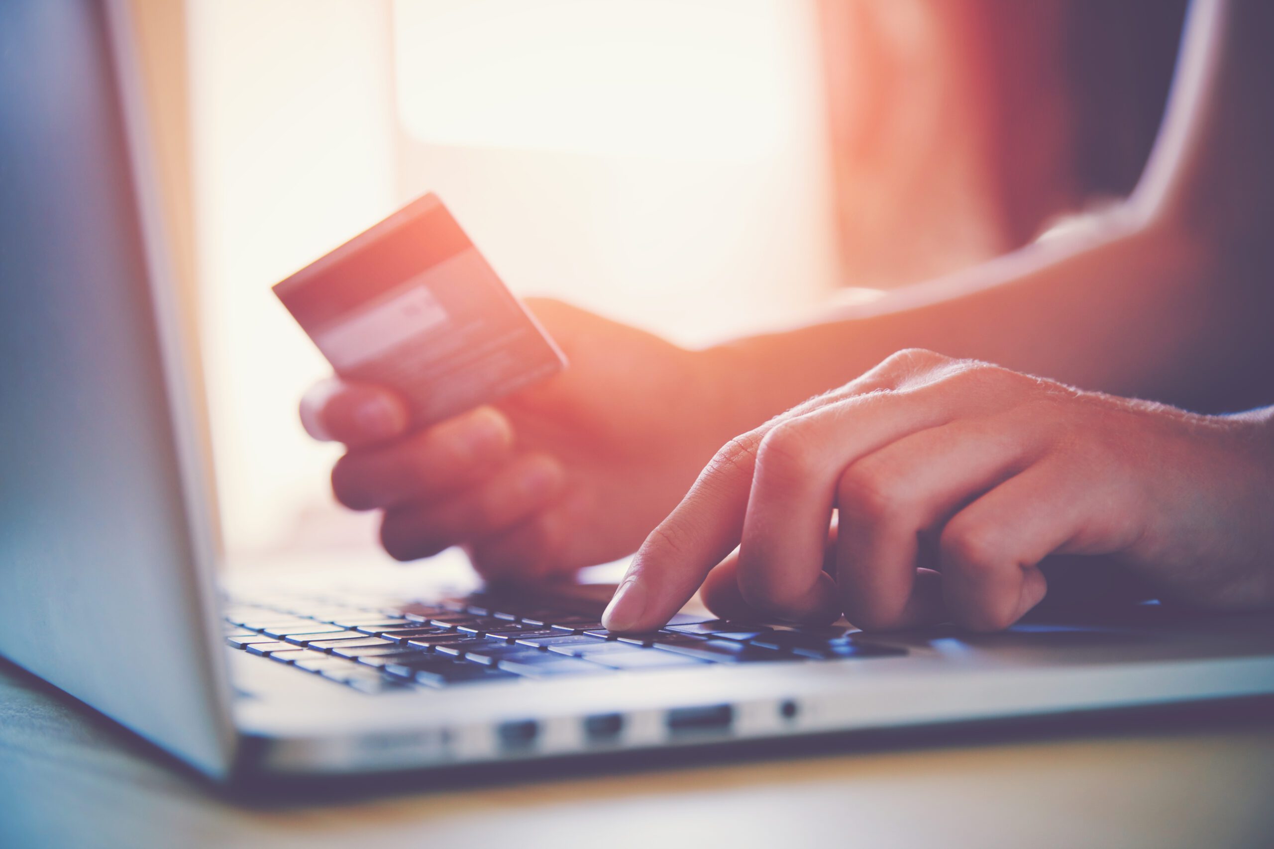 person using laptop with credit card in hand