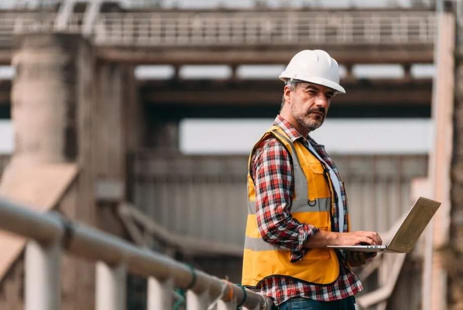 image of construction worker in safety vest using laptop computer