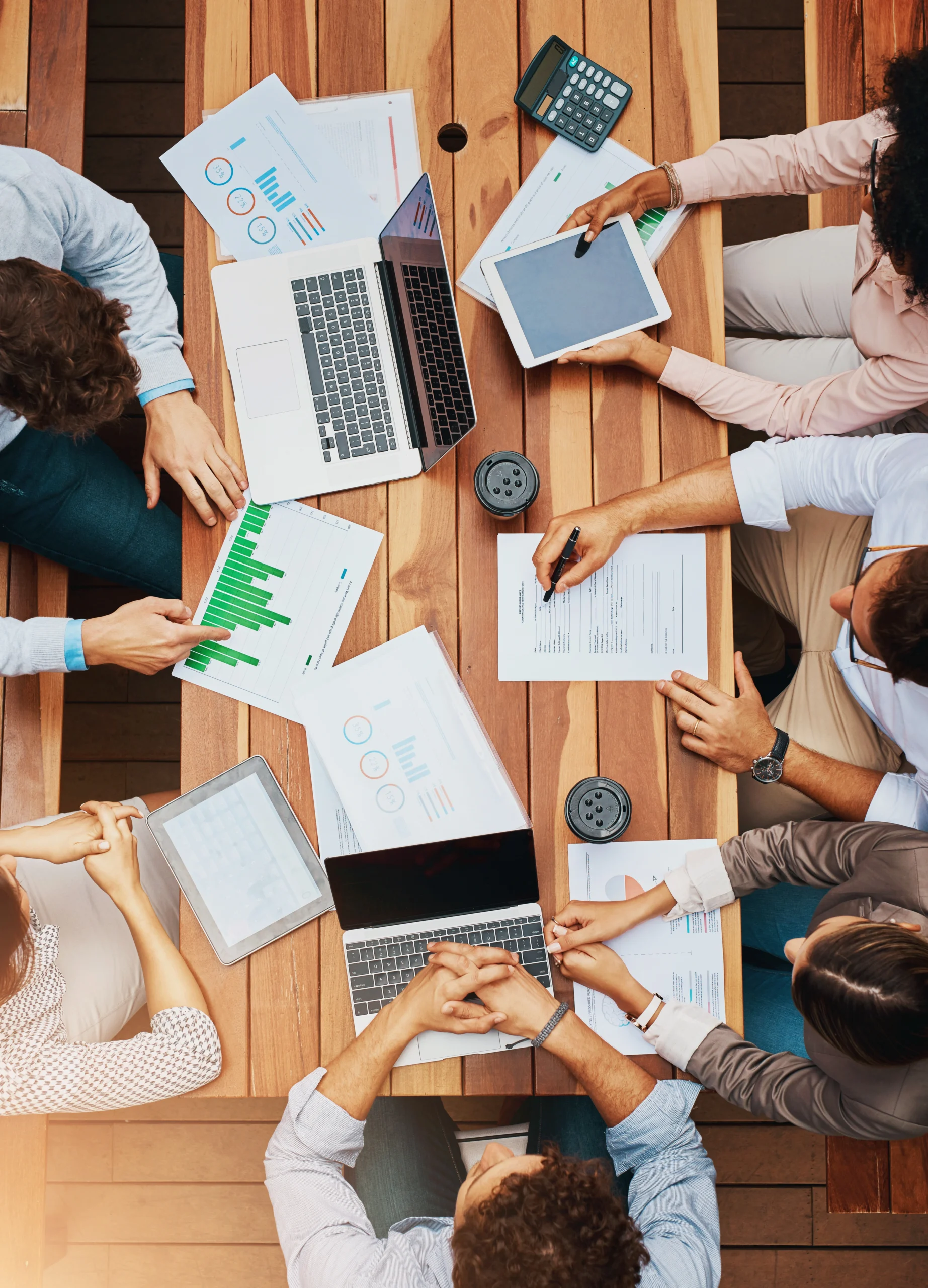 employees around table with laptops and graphs business planning